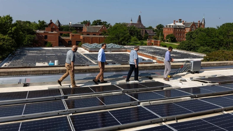Technicians surveying rooftop solar array at distributed energy site