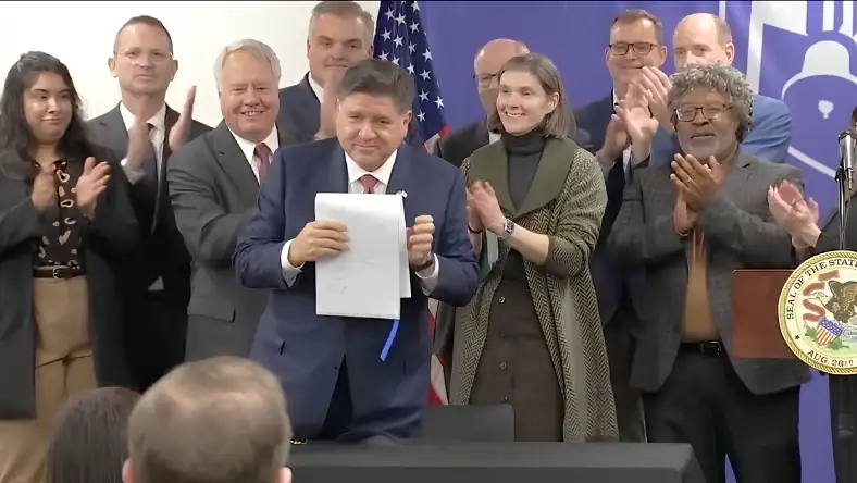 Man holds a signed document while officials applaud during a government signing ceremony